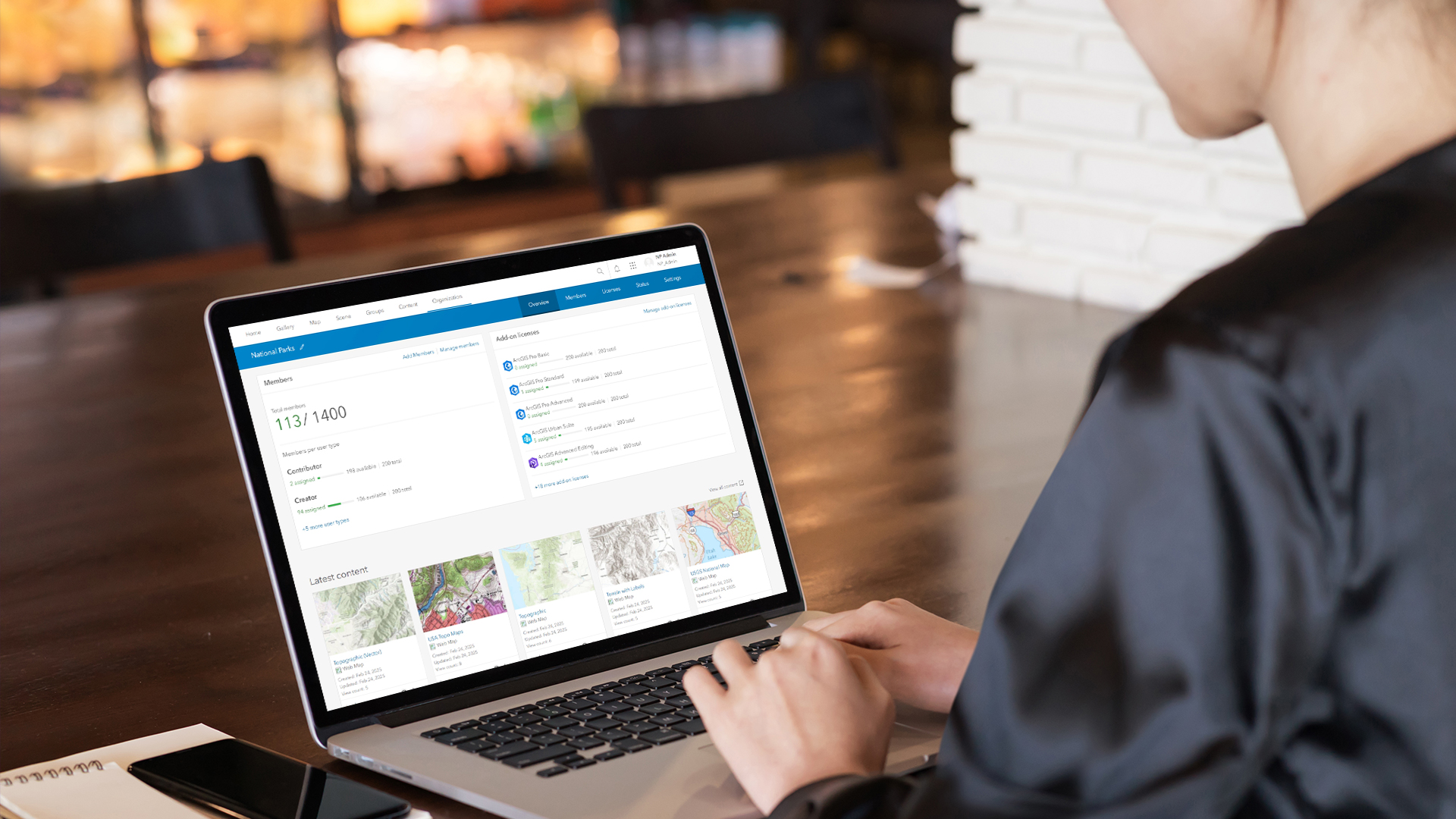 Personne assise à une table et utilisant un ordinateur portable avec un écran affichant des mesures, des liens et des cartes 