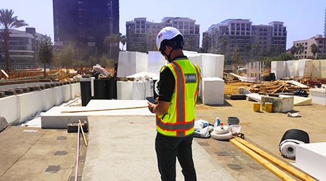 Personne portant un gilet de sécurité et un casque de chantier au milieu d’une zone de construction sur le toit d’un immeuble d’une ville
