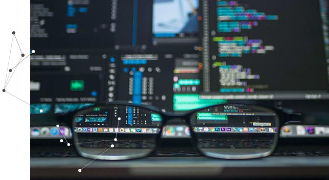 Une paire de lunettes posée sur un clavier d’ordinateur portable dont l’écran affiche des lignes de données 