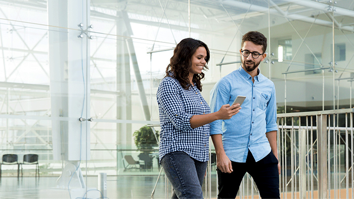 Une femme et un homme marchant dans un bâtiment en regardant un téléphone mobile