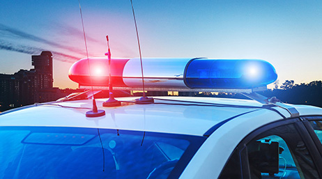 Toit d’une voiture de police avec des gyrophares rouges et bleus au soleil couchant 