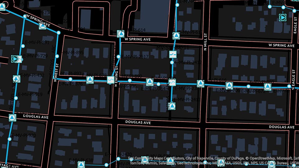 Carte noire avec des lignes bleues connectées et des routes rouges représentant des conduites d’eau et des valves dans un quartier résidentiel