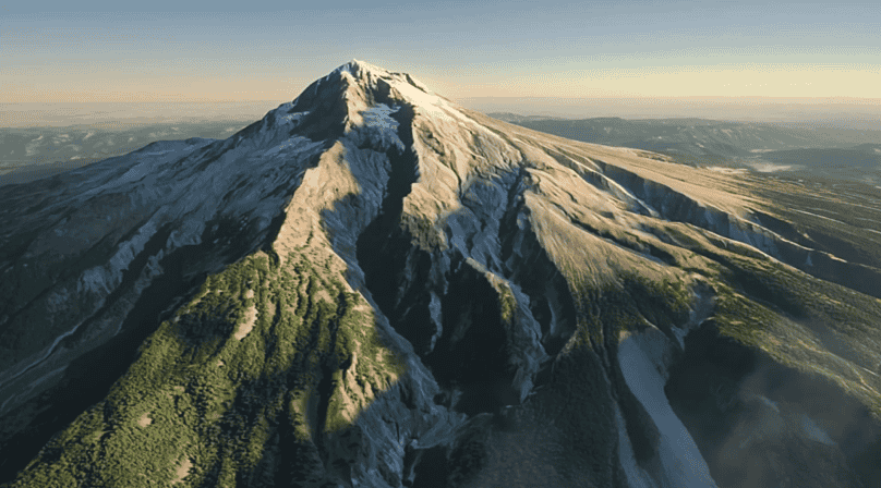 Vue aérienne d’une montagne au sommet enneigé avec des pentes verdoyantes