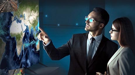 Deux personnes en costume discutant devant un écran mural qui affiche une carte colorée des pays dans une salle de conférence moderne à l’éclairage tamisé