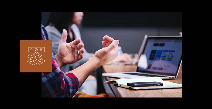 Image des mains d’un homme devant un bureau avec un ordinateur portable, un carnet et un téléphone portable
