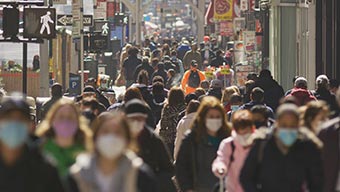 Trottoir bondé avec une foule de gens qui marchent et portent un masque