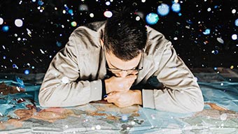 Jeune homme avec des lunettes regardant une grande carte du monde
