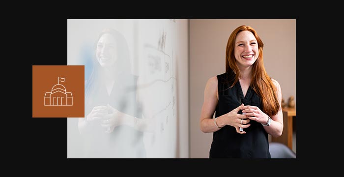 Jeune professionnelle souriante tenant un marqueur devant un tableau blanc