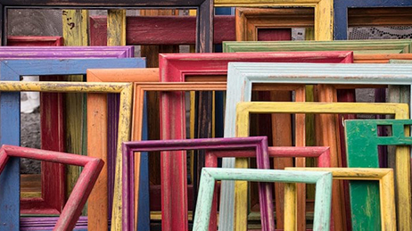 Assortiment de cadres de diverses couleurs et tailles posés contre un mur 