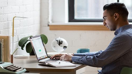 Un homme à un bureau tapant sur un clavier d’ordinateur portable et lançant un modèle ArcGIS Hub