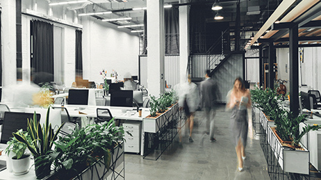 Grand immeuble de bureaux moderne avec des tables et des bureaux et plusieurs employés qui marchent