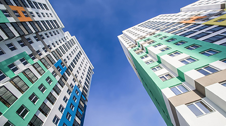 Deux immeubles d’appartements multicolores en vert, bleu et blanc sur un fond de ciel bleu avec des nuages