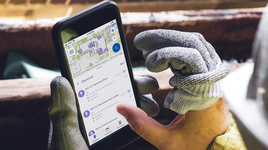 Opérateur de maintenance tenant un téléphone mobile qui affiche une carte indoor