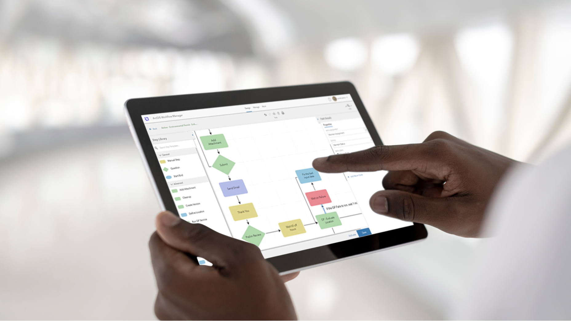 Personne tenant une tablette qui affiche des cases multicolores reliées par des flèches représentant un organigramme