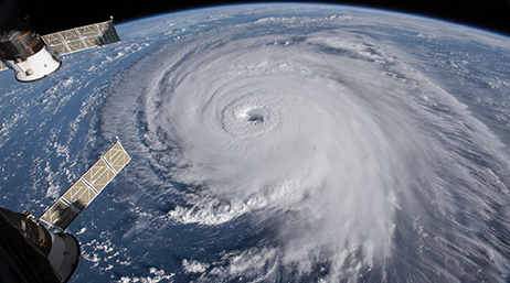 Photo satellite prise depuis l’espace représentant le sommet d’une tornade tourbillonnante sur l’océan bleu avec la courbure de la Terre visible en arrière-plan 