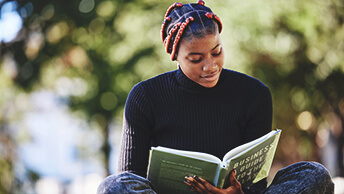 Femme assise à l’extérieur en train de lire un livre