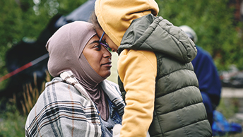 Une femme et un enfant se regardent, le front appuyé l’un contre l’autre