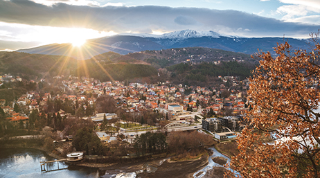 Vue aérienne de Sofia, en Bulgarie, avec une rivière, une architecture densément peuplée, des montagnes et le soleil brillant à travers les nuages