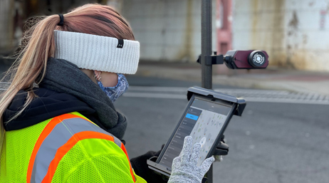 Travailleur nomade portant des gants en laine, une protection du visage et une veste jaune fluo et travaillant sur une tablette