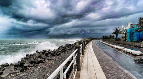 Photo d'une promenade le long d'une plage orageuse sous un ciel chargé de nuages sombres
