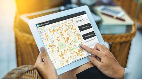Photo d’une paire de mains consultant une carte sur une tablette avec une salle de séjour marron et bleue visible en arrière-plan