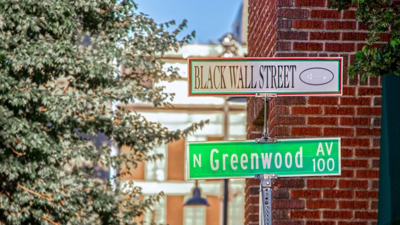 Panneaux de signalisation de Black Wall Street et Greenwood Avenue près d’un bâtiment en briques