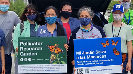 Photo d’un groupe de personnes en tenue décontractée portant des masques et des panneaux verts et bleus