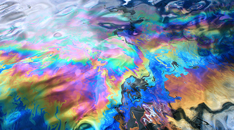 Gros plan de la surface au reflet d’arc-en-ciel d’une eau recouverte de pétrole