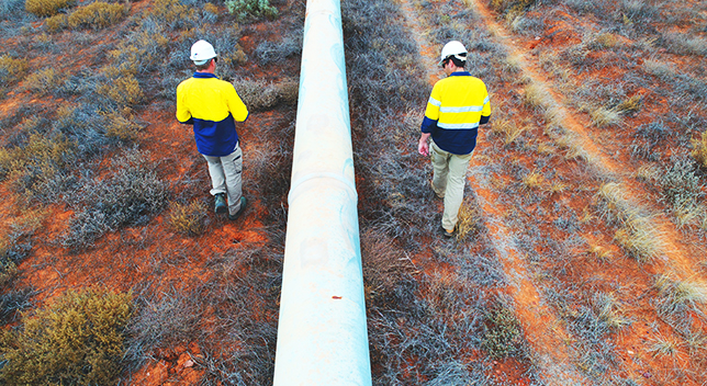 Deux opérateurs de pipeline marchant pour inspecter un pipeline