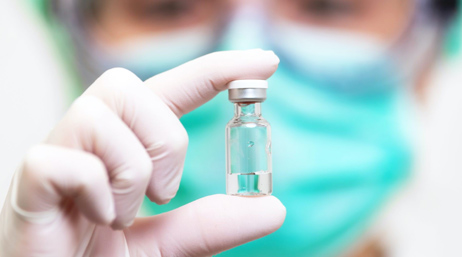 Personne portant un gant et tenant un vaccin