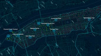 Une carte des rues de Manhattan en bleu et vert foncé parsemée de points cartographiques en bleu