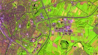 Image satellite d’une ville aux teintes violettes et vertes fluorescentes avec plusieurs autoroutes se croisant.