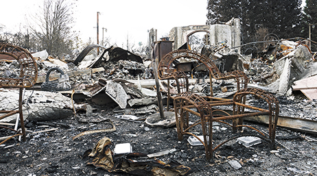 Terre calcinée, chaise et structure brulées après un incendie en Californie