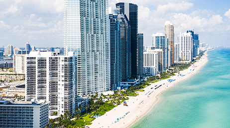 Front de mer de Miami Beach, Floride, avec ses grands immeubles et des gens sur ses plages de sable blanc, au bord d’une eau turquoise