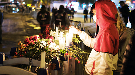 Personne se tenant devant des bougies allumées sur un autel de fortune en mémoire des victimes d’un séisme