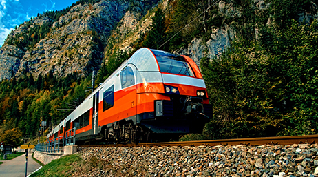 Train de voyageurs orange et blanc se déplaçant à flanc de montagne