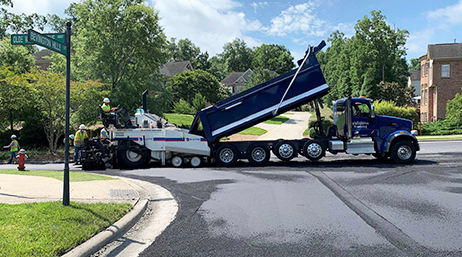 Travailleurs utilisant du matériel de maintenance des routes dans une rue d’un quartier 