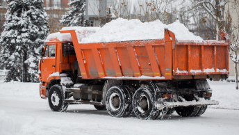 Lourd camion de transport orange chargé de neige