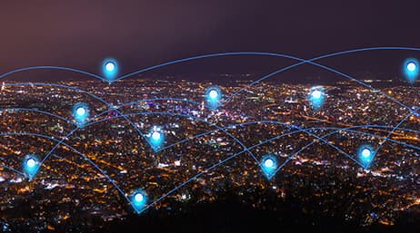 Vue aérienne nocturne d’une ville avec des icônes bleues de localisation