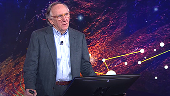 Jack Dangermond, PDG d'Esri, sur un podium devant un fond bleu et rose