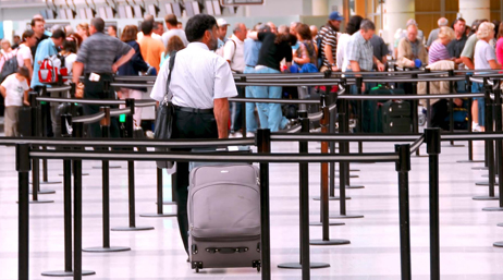 Un homme avec une valise rejoint une file d'attente à l'aéroport