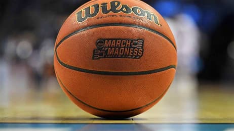 Ballon de basket posé au premier plan sur un terrain de basket avec un arrière-plan flou